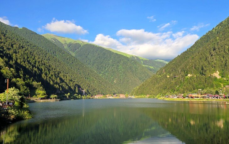 uzungöl göl çevresi manzarası, dağların yansıdığı sakin su yüzeyi ve yeşil vadiler